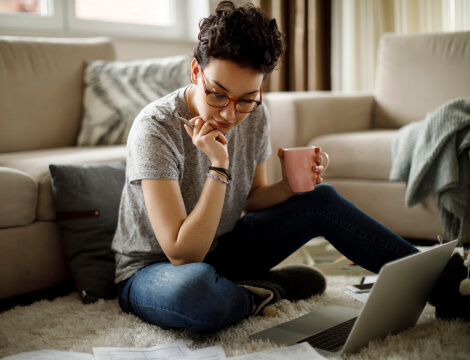 A mom is sipping coffee while working from home on a laptop